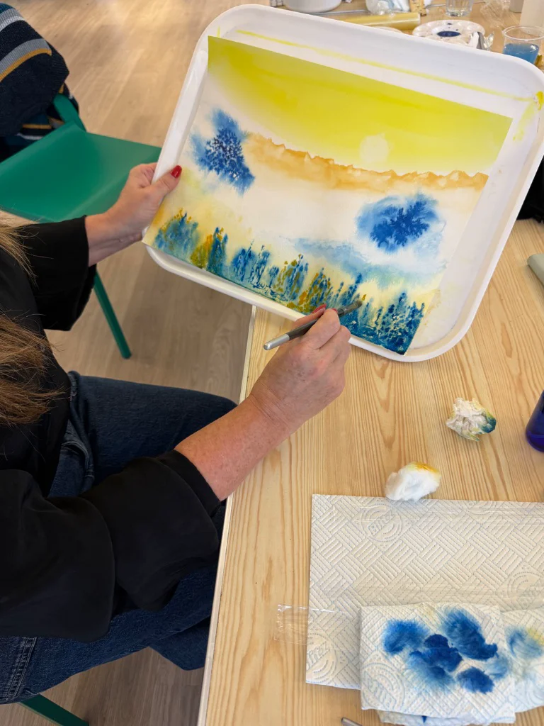 Workshop participant creating watercolour art with wet on wet technique demonstration